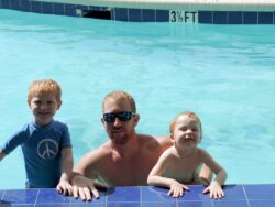 A man and two children posing at the edge of a swimming pool with a depth marker of 3 1/2 feet in the background.