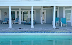 A serene poolside area with neatly arranged chairs and flip-flops placed by the pool's edge.
