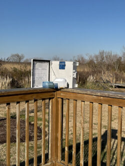 Open portable cooler on a wooden deck with grassland in the background.