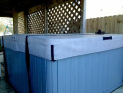 A hot tub with a closed cover located on a wooden deck with lattice privacy panels.