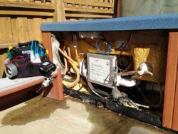 An opened outdoor pool equipment storage area with various tools and plumbing visible.