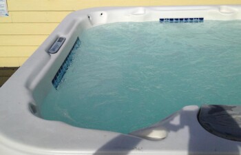 Outdoor hot tub with clear water under daylight.